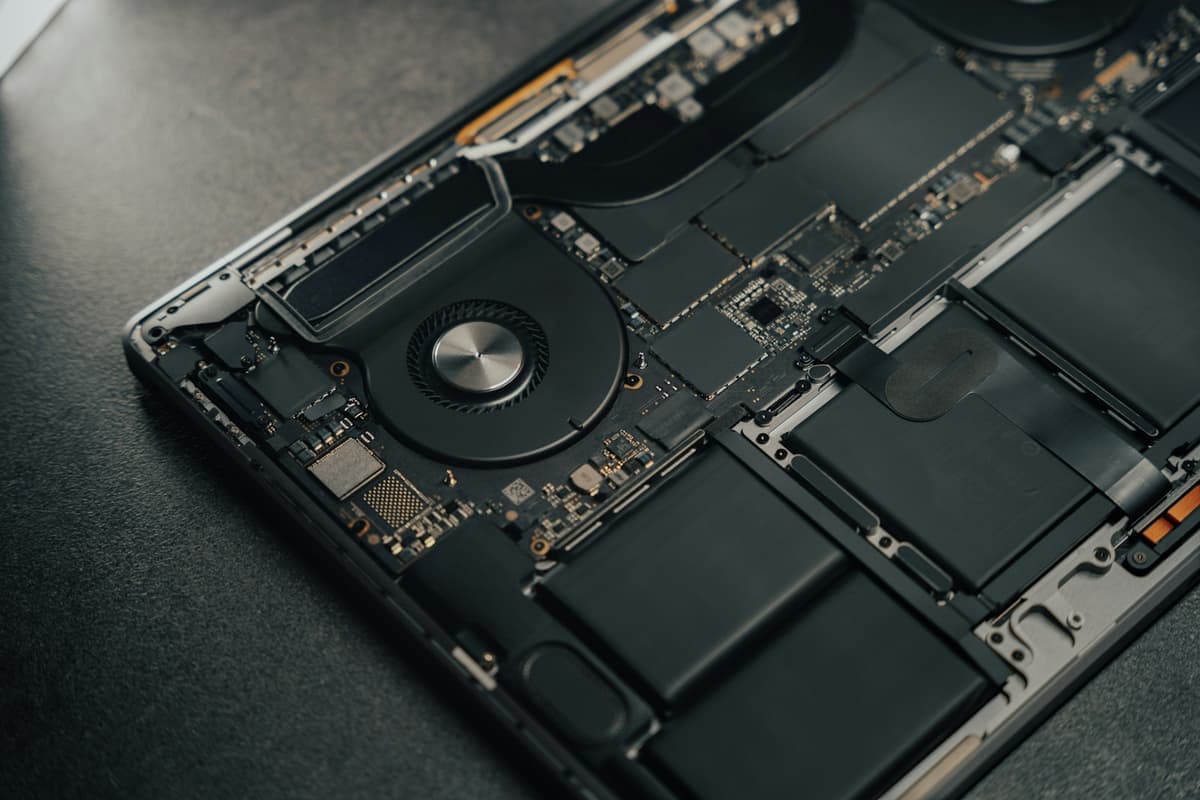 The inside of a laptop with the base panel removed, showing the cooling fan, heat pipe and battery
